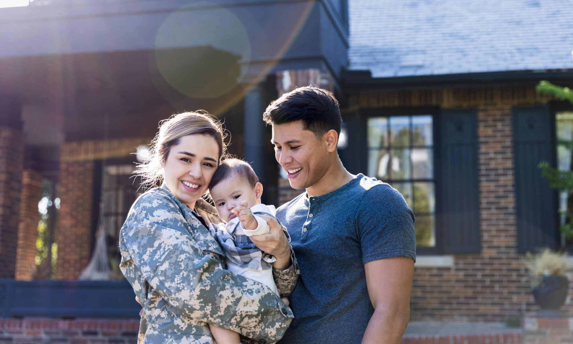 Female service member holds here baby as her husband looks on.